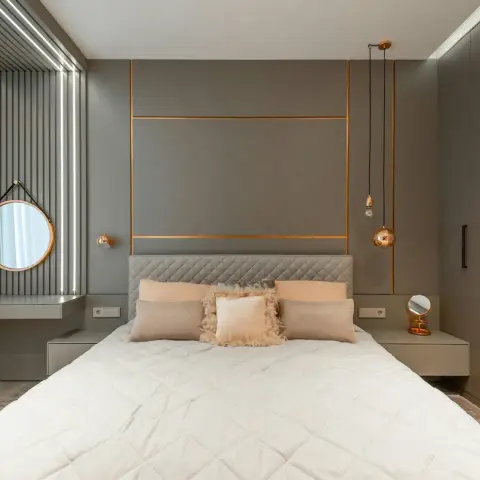 Grey upholstered bed wall inlaid with slim rose-gold lines, twin copper globe pendants dropped on cords