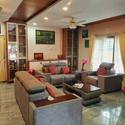 Grey upholstered sofa set with rust cushions around a curved glass-top coffee table