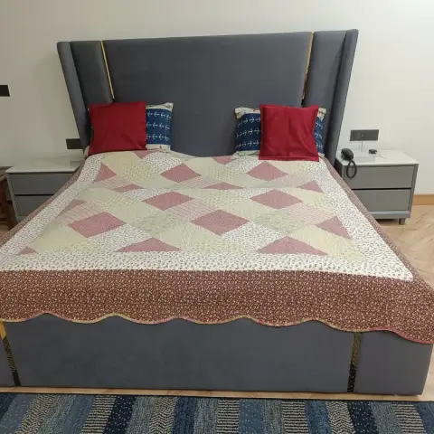 Grey velvet winged bed with brass inlay strips and matching grey drawer nightstands