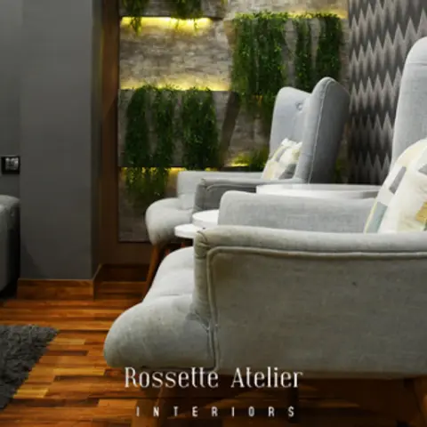 Grey wingback armchairs facing a backlit vertical-garden feature wall in a chevron-wallpapered lounge corner, wood flooring and a grey shag rug.