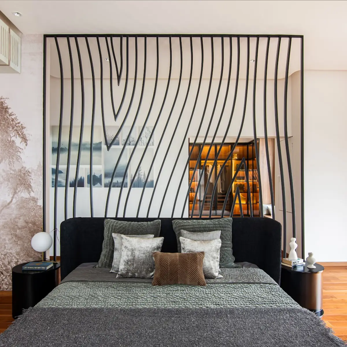 Master bedroom with a sculptural wave-patterned black metal headboard screen framing a glimpse of the attached walk-in wardrobe