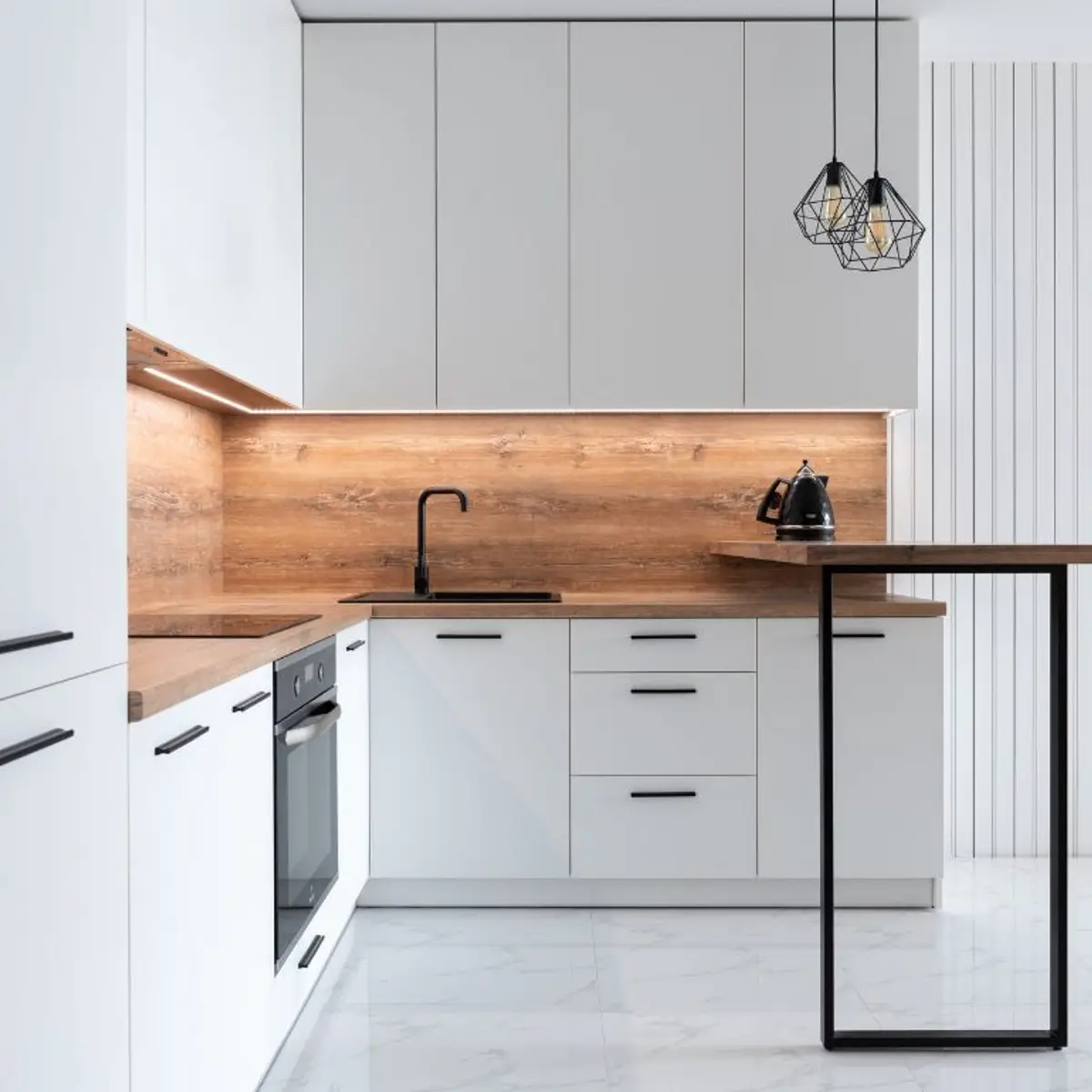 White handleless kitchen with wood-panel backsplash and pendant lights