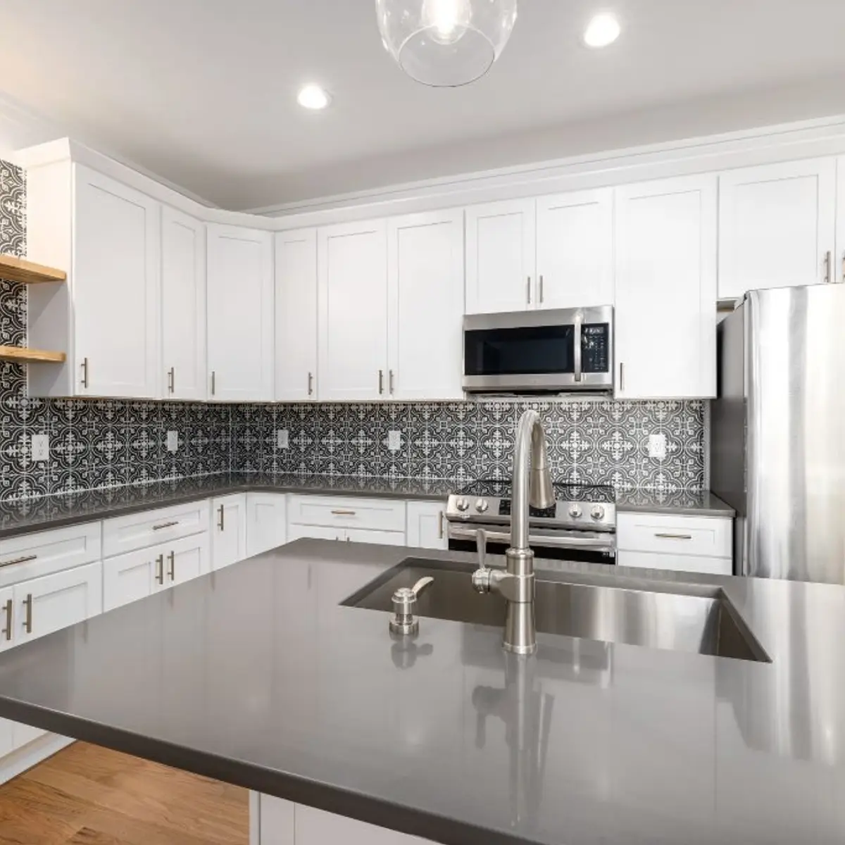 White shaker kitchen with a bold black-and-white patterned tile backsplash rising to the ceiling
