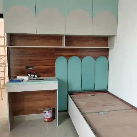 Half-finished single bed platform with an arched mint upholstered headboard, a matching study desk and mint-and-white overhead lofts against a fluted walnut