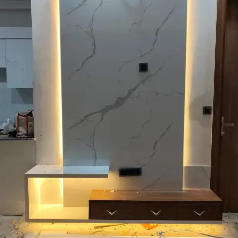 Half-finished TV wall clad in one tall Statuario-look porcelain slab backlit on all four edges