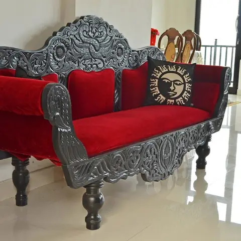 Hand-carved dark-wood settee upholstered in red velvet with ornate floral and bird motifs