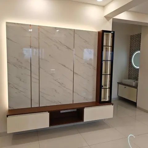 Handed-over TV wall of four high-gloss marble-look panels in a backlit halo, a walnut floating console with two ivory drawers and an open cable slot