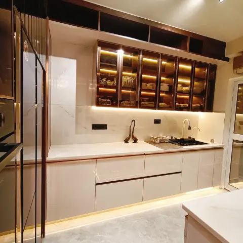 Handleless ivory gloss base run with rose-gold J-profile groove, black granite undermount sink and a brass duck sculpture