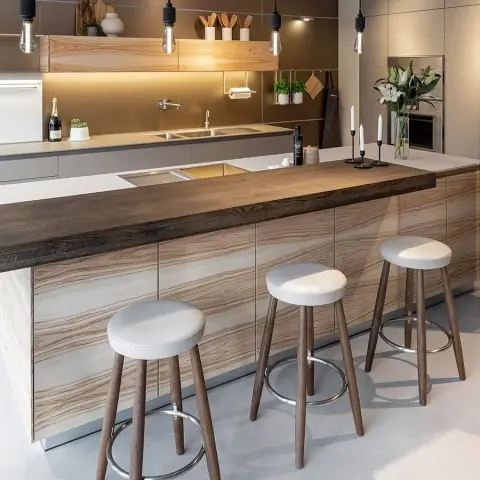 Handleless kitchen island carrying a thick timber breakfast-bar slab over its stone top
