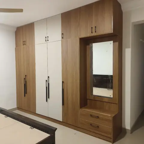 Handover shot of a bedroom's teak-and-white laminate wardrobe run with a loft row and an integrated mirror-and-drawer dresser bay