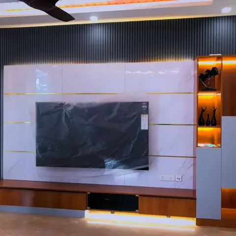 Handover shot of a TV wall: charcoal fluted panelling behind a white marble-look slab with brass inlay lines