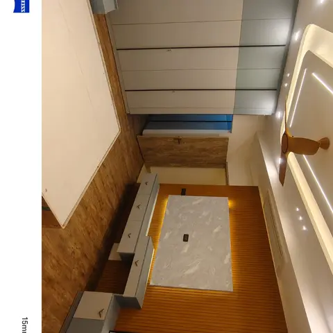 Handover-stage bedroom shot sideways from the doorway: a bare plywood box-bed platform faces a fluted teak wall with a backlit grey stone panel and a