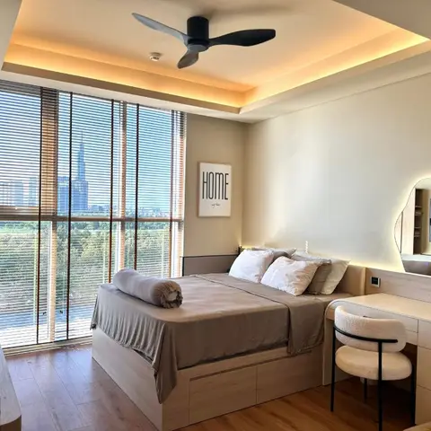 High-rise bedroom with a cove-lit tray ceiling, floor-to-ceiling window blinds and a city skyline view