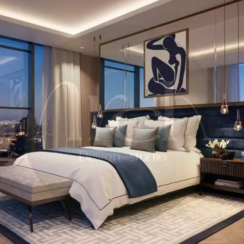 High-rise bedroom with a navy channel-tufted upholstered headboard wall, hanging bedside pendant lights and a floor-to-ceiling city night view.
