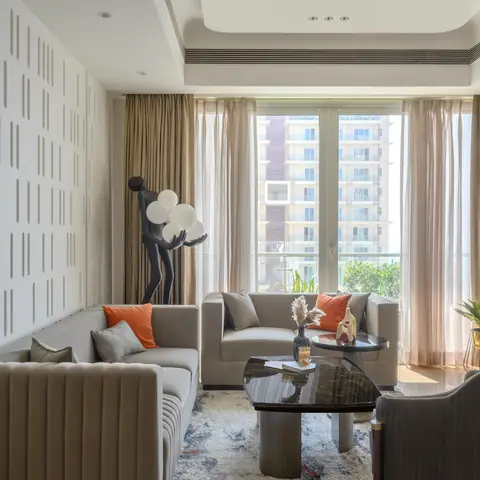 High-rise living room with channel-tufted taupe sofas around a dark stone coffee table, a slatted feature wall and a sculptural floor lamp.