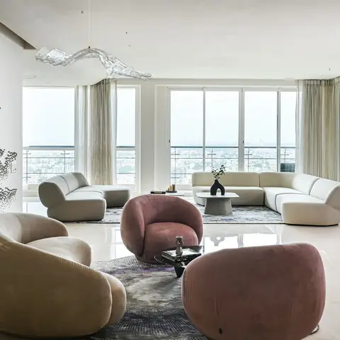 High-rise living room with sculptural pebble-shaped cream and dusty-rose velvet seating, a glass drip-form pendant light, a pixel-dot wall art installation