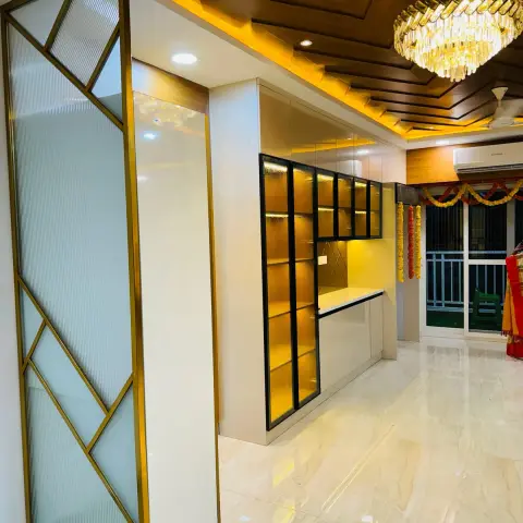 Home entrance foyer with a geometric gold-framed fluted-glass partition screen, an angular wood-clad ceiling with a crystal chandelier