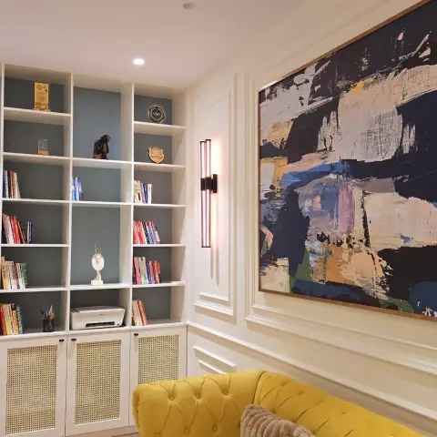 Home library with a grid bookcase on sage-green backing over cane-webbing base shutters