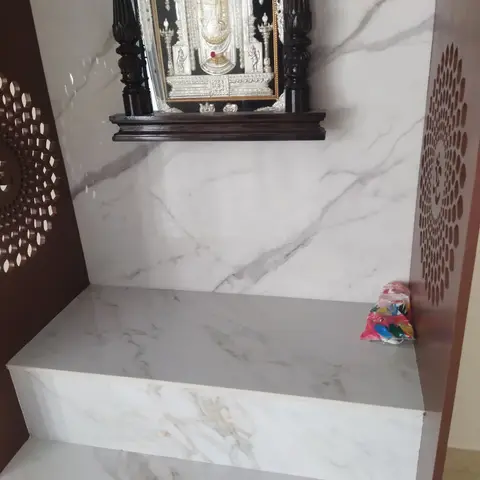 Home pooja unit with a marble-clad backwall, a carved dark-wood mandap frame holding a silver Tirupati Balaji idol panel, and jaali side screens.