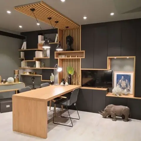 Home study built around a long oak table under a slatted timber ceiling raft, with black panelling carrying stepped oak open shelves