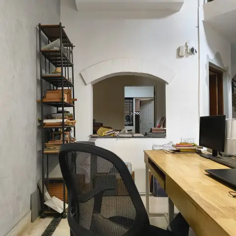 Home study nook with a light wood desk and mesh office chair below an arched interior window cut-out