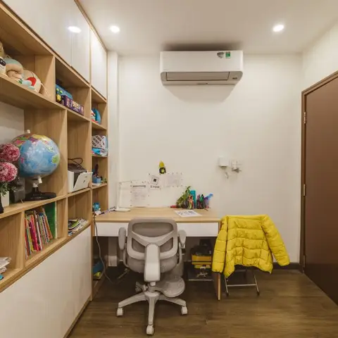 Home study nook with a wood-and-white built-in desk and floor-to-ceiling wood shelving stacked with books, toys and a globe.