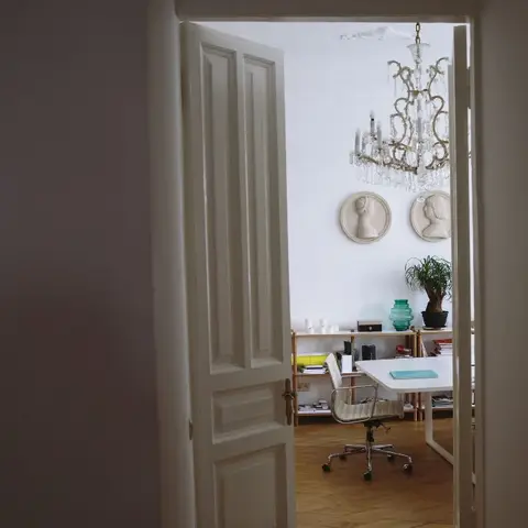Home study seen through a doorway, with a white desk and office chair, open bookshelf