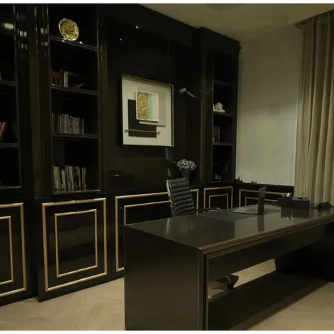Home study with a full-wall black gloss and gold-trimmed bookshelf-cum-cabinet unit and a matching executive desk.