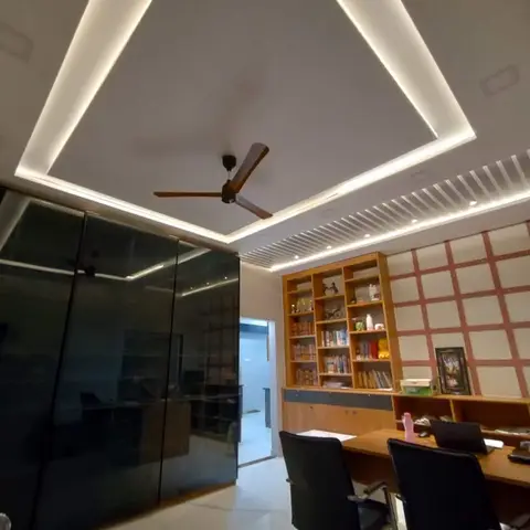 Home study with a glossy black wardrobe wall, a wooden bookshelf and desk, and a triangular cove-lit false ceiling with a ceiling fan.