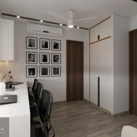 Home study with a long built-in desk facing a nine-photo black-and-white gallery wall, beside a fluted-panel corner wardrobe.