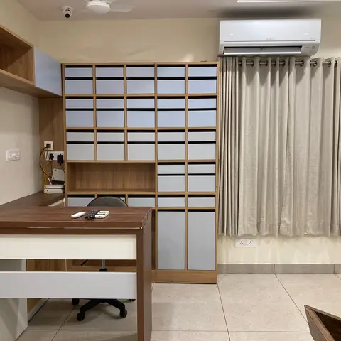 Home study with a wall-to-wall wood-framed storage unit of grey drawer-fronts, an L-shaped work desk with an office chair