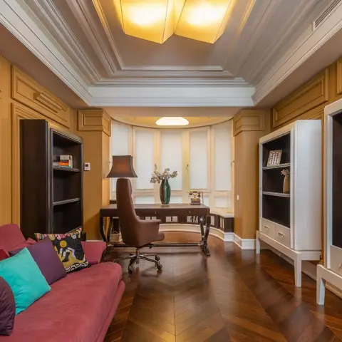 Home study with mustard panelled walls, a curved bay window desk nook, chevron-pattern wood flooring and a built-in dark-wood media wall