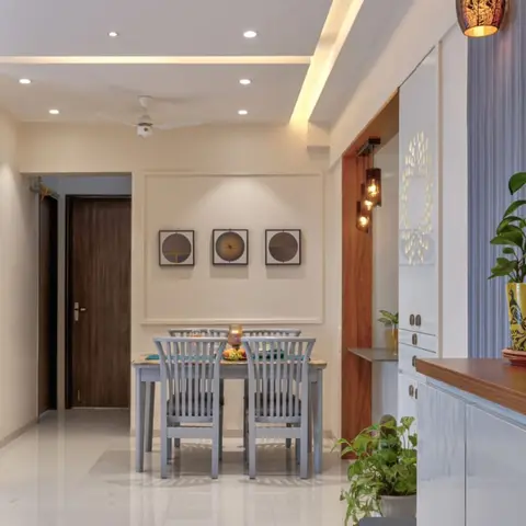 Indian apartment dining nook with grey wooden chairs and a marble-top table beneath a cove-lit POP ceiling