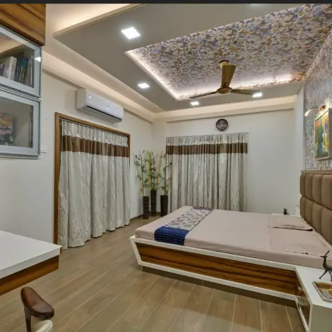 Indian bedroom with a floral-wallpapered central ceiling panel ringed in cove light around the fan, brown-banded pelmet curtains on two walls