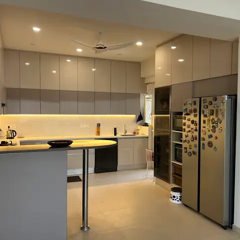 Indian home kitchen with glossy handleless cabinetry, a backlit veined-stone backsplash, a round-topped breakfast counter extension