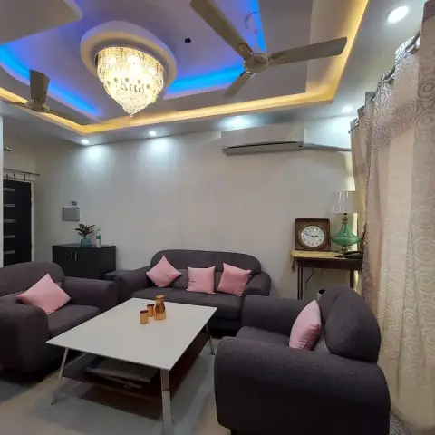 Indian living room with a charcoal fabric 3+1+1 set dressed in blush cushions around a white rectangular coffee table