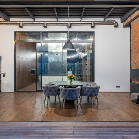 Industrial-loft dining area with an exposed duct ceiling, a brick accent wall, and tufted velvet chairs around a round table