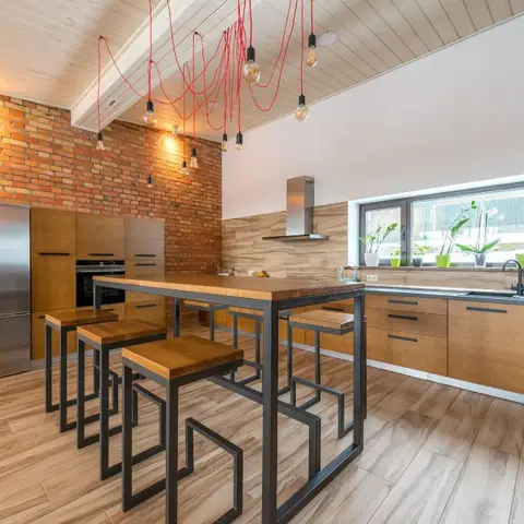 Industrial-style kitchen with an exposed red brick wall, a tangled cluster of red-cable pendant bulbs