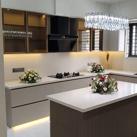 Island kitchen with glossy taupe shutters, bronze-framed glass wall cabinets, a fluted dark-wood island and a tiered crystal chandelier overhead.