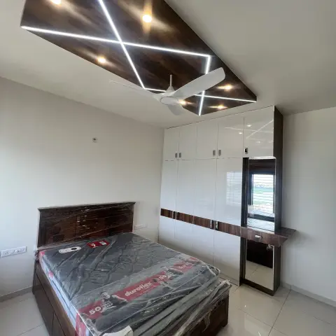 Just-handed-over bedroom with the mattress still in its factory wrapping on a dark wooden storage bed, under a walnut ceiling raft crossed by LED profile lines.