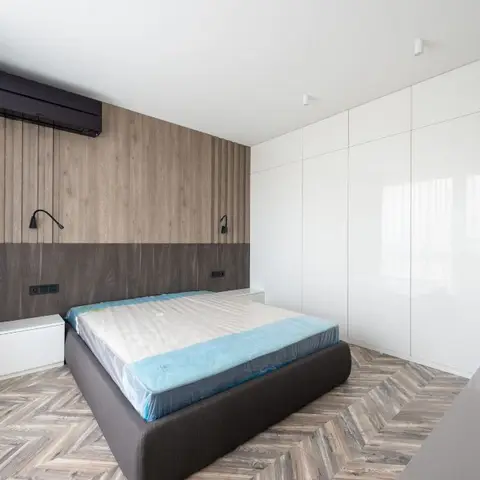 Just-handed-over bedroom with the mattress still in its factory wrapping on a dark upholstered bed base