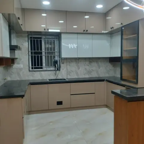 Just-handed-over U-shaped kitchen in mocha gloss shutters with black granite counters, a stainless sink under a grilled window still wrapped in installer film