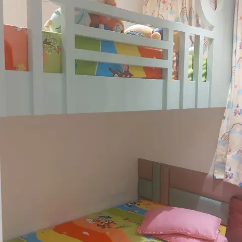 Kids' bedroom bunk bed with a mint-green built-in frame, Tom and Jerry printed bedding, and rainbow-print curtains.