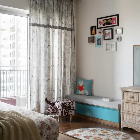 Kids' bedroom corner with a curated gallery wall, a cow-print ottoman, a turquoise storage bench and a wicker dresser.