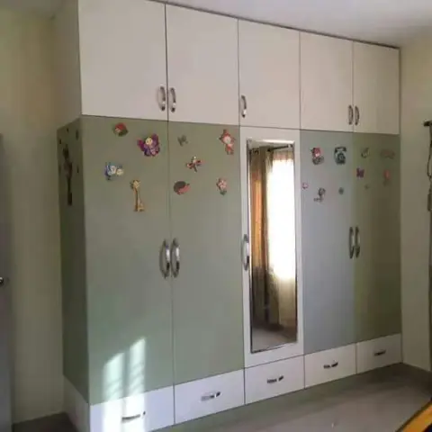 Kids' bedroom wardrobe wall in mint-green and white shutters decorated with butterfly and animal stickers