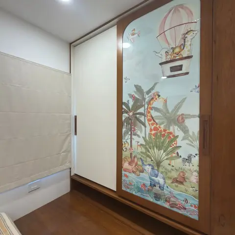 Kids' bedroom wardrobe with a hand-painted jungle-safari mural on a glass sliding door in a warm wood veneer frame, striped bed visible in the foreground.