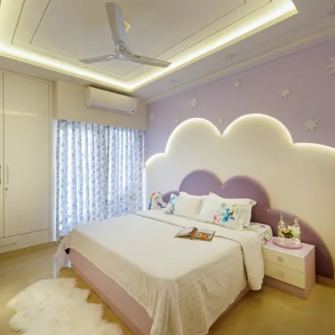 Kids' bedroom with a backlit cloud-shaped upholstered headboard against a star-painted lavender wall, a sheepskin rug, and a layered cove-lit ceiling.