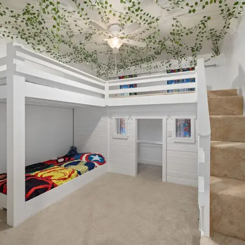 Kids' bedroom with a built-in white loft bunk bed over a playhouse nook, carpeted stairs to the loft, and a faux vine installation on the ceiling