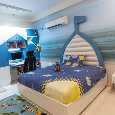 Kids' bedroom with a custom boat-shaped bed against an ocean-mural wall, a built-in blue study unit, and an animal-print area rug.