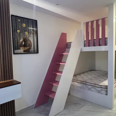 Kids' bedroom with a custom white-and-dusty-pink built-in bunk bed complete with a slide and ladder steps.